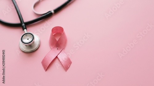 A pink ribbon alongside a stethoscope on a pale pink backdrop symbolizing breast cancer awareness and medical health