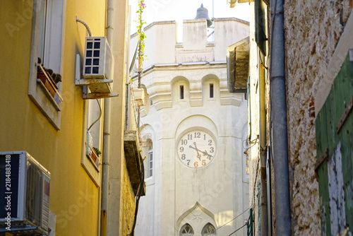 Obraz na plátně Clock face on Sat Kula tower in Herceg Novi framed by closely spaced buildings