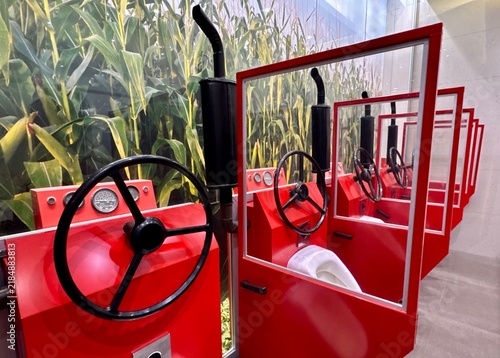 Urinals in the restroom shaped like a combine harvester cab, set against a backdrop of a cornfield