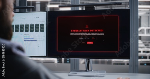 Cybersecurity Specialist Monitors Data Center After Cyber Attack Alert, Analyzing Dashboards on Dual Screens While Responding to Threats, Protecting Servers, Networks, and Digital Systems Securely.