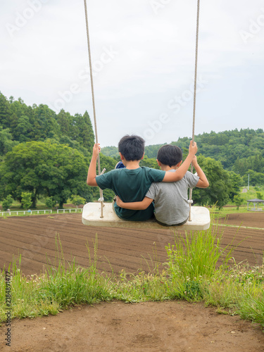 Tapety artystyczne 高台のブランコで肩を組み景色を眺める兄弟