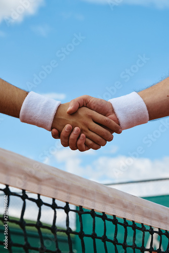 Картината върху платно Vertical image of woman and man shaking hands over tennis net after match