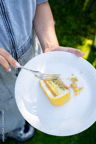 Close up of woman hand with fork eating slice of lemon cake