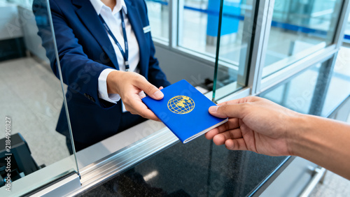 Traveler handing blue passport to agent through airport security glass