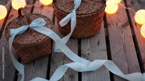 Two Woven Baskets with Blue Ribbons and String Lights on Wooden Surface.