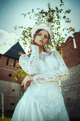 Young Woman in Traditional Russian Attire Standing by Red Brick Fortress Wall