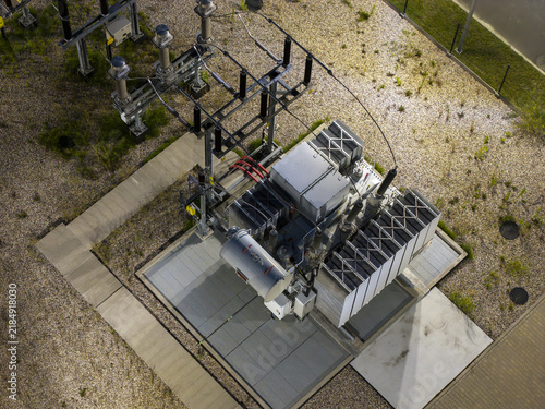 Aerial view of a 11015kV transformer substation with high-voltage equipment, cooling fins, and gravel ground in Poland.