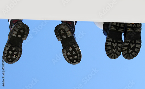 Fotografie Pies con suela de zapato colgando en muro espacio editable texto y cielo azul