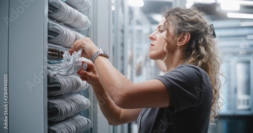 Female IT Technician Performs RJ45 Patching Inside Server Rack, Routing Network Cables Through Cable Managers and Checking Physical Connections For Structured Cabling Maintenance and Service.
