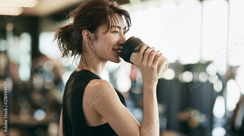 ジムで運動後に美味しそうにプロテインを飲む女性