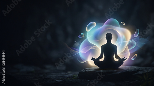 Silhouette of person meditating with glowing colorful energy aura and copy space on dark background