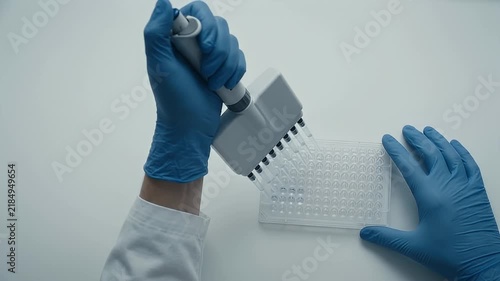 Scientist Pipetting Liquid into Multiwell Plate in Modern Laboratory Close Up
