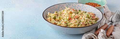 Tabbouleh salad couscous vegetables bowl Middle Eastern blue background copy space