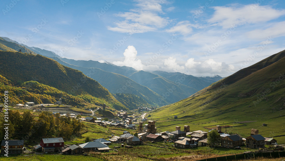 Fototapeta premium Landscape photograph of Ushguli village with Svan towers in mountain valley under blue sky in Svaneti Georgia.