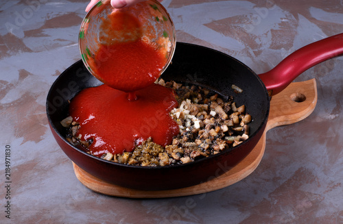 Adding tomato sauce to the mushroom base. Mushrooms, onions, and garlic are finely chopped and fried in a pan with spices and salt. Step by step