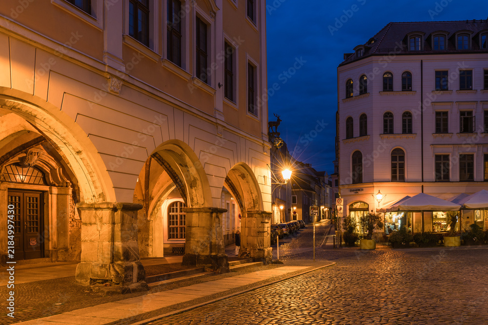 Fototapeta premium Stunning night cityscape of Görlitz, Germany. Beautifully illuminated historic Old Town, medieval architecture, and bright street lights highlighting the rich cultural heritage at dusk.
