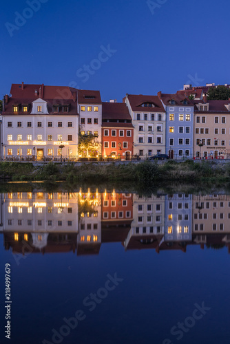 Beautiful night cityscape of Zgorzelec, Poland. Illuminated city streets, historic architecture, and the peaceful Neisse river reflecting bright evening lights along the European border.