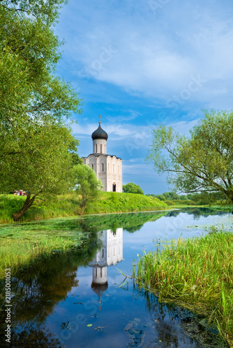Quadro su tela Church of the Intercession on the Nerl with Reflection in River Surrounded by Tr