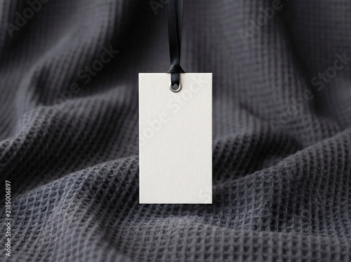 Blank white price tag hanging on dark fabric background for retail branding mockup