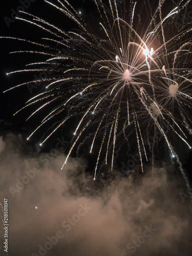 Sparkling fireworks explode over smoke night sky