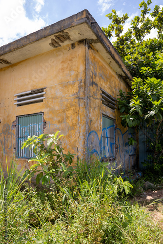 Bild auf Leinwand Weathered abandoned building with cracked yellow walls, Son Tra Peninsula, Da Na
