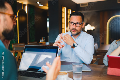 Business colleagues discussing project strategy over laptops during a casual meeting in a modern cafe