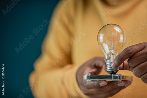 Konstfotografi A close-up shot of a man holding a glowing vintage light bulb in an office, symb