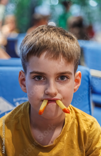 Young boy smiles with two sticks in his mouth