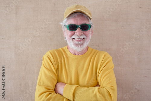 Фотография Happy senior man with a white beard, wearing a yellow shirt, green sunglasses, a