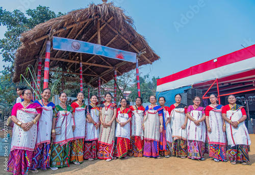 Obraz na płótnie Mising women standing before the ceremonial thatched structure (Murong), dressed in vibrant during Ali-Aye-Lhigang at Sonaighuli in Guwahati,Assam,India on 19 february 2025