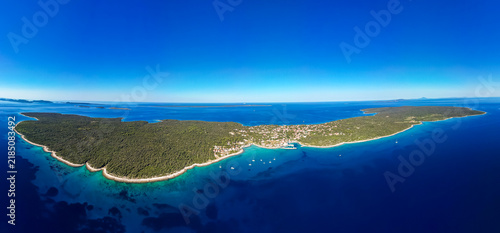Aerial drone panorama of the western part of Silba Island, Croatia, surrounded by the crystal-clear Adriatic Sea. The picturesque coastal village, turquoise shoreline and Mediterranean vegetation