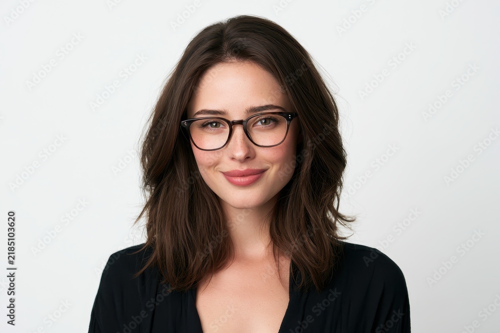 Obraz premium Bright studio portrait of a happy brunette with glasses in a minimal white setting