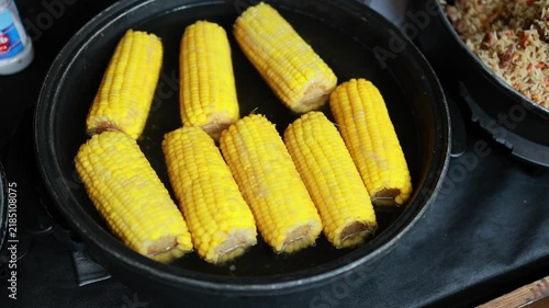 Corn placed in a pot for cooking with rice and spices in the background