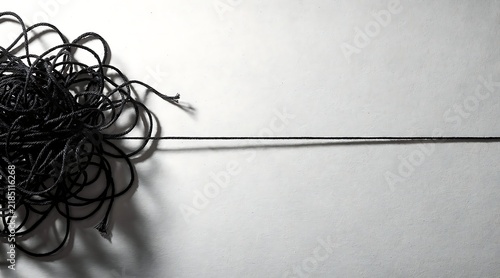 Tapety artystyczne A tangled black string gradually unravels into a single straight line on a clean white background, symbolizing clarity emerging from complexity and offering a visual metaphor for problem-solving.