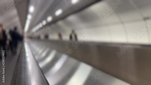 Blurred background of moving travelator with blurred people commuting