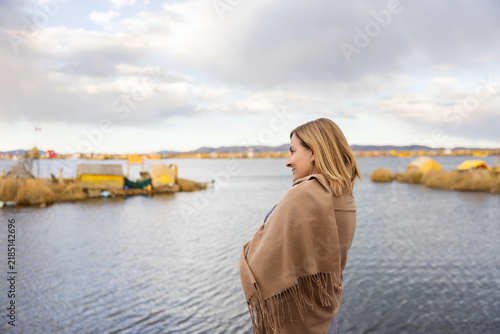Foto Woman wrapped in a warm shawl overlooking a peaceful lake on a cold day