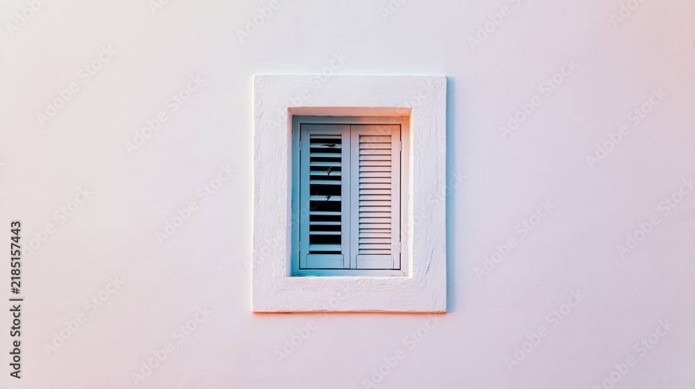 Fototapeta premium Minimalist building facade presenting a small shuttered window. Soft evening light creating subtle pastel color shifts on the wall