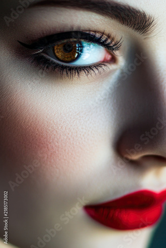 Close-up photo of a woman with bold red lipstick and makeup. vertical frame