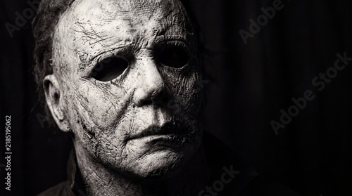 A close up view of a distressed white human face mask against a black background with shown close portrait mask deep texture