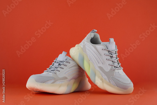 White sport sneakers with colorful sole on red background