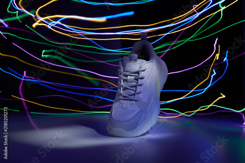 White sneaker surrounded by vibrant neon light painting