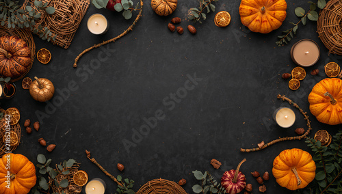 Autumn flat lay border of pumpkins and small candles on dark textured background with halloween seasonal background vegetable decoration november thanksgiving copyspace celebration