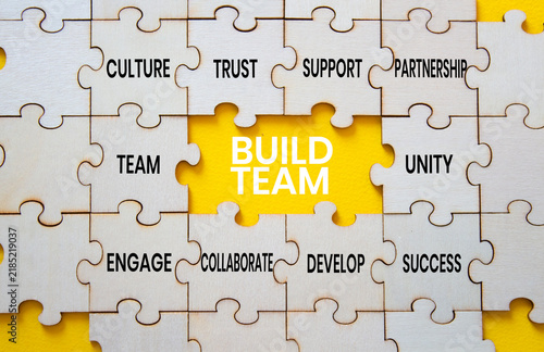 Build team symbol. Concept words build team on puzzle pieces. Team building and collaboration concept. Yellow background. Copy space.