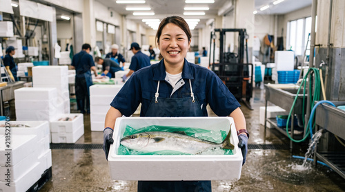 Naklejka 鮮魚市場・水産加工施設で魚を運ぶ女性スタッフ