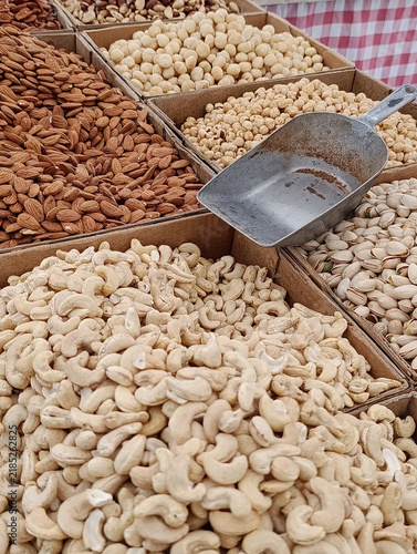 Market stall display with assorted bulk nuts for sale by weight, including walnuts, cashews, almonds, and mixed nuts.