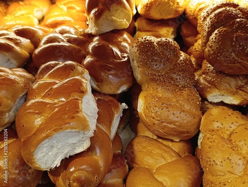 Market stall display with traditional challah bread, braided Shabbat loaves, and Jewish egg bread for sale.