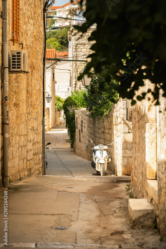 Fotografie Narrow stone alley with a scooter in Hvar old town Croatia
