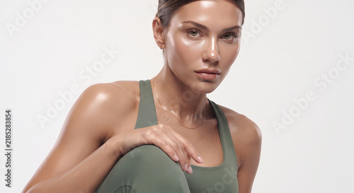 Close up portrait of a confident athletic woman in green sportswear looking at camera