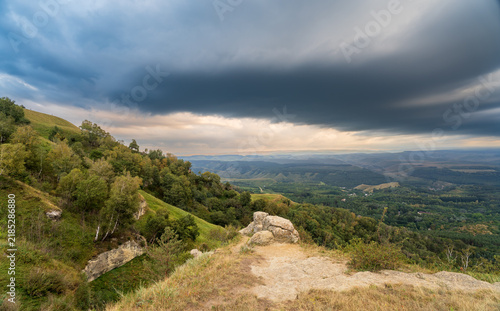 фотографія A mountain range covered in the wild woods illuminated by the golden light of the setting sun