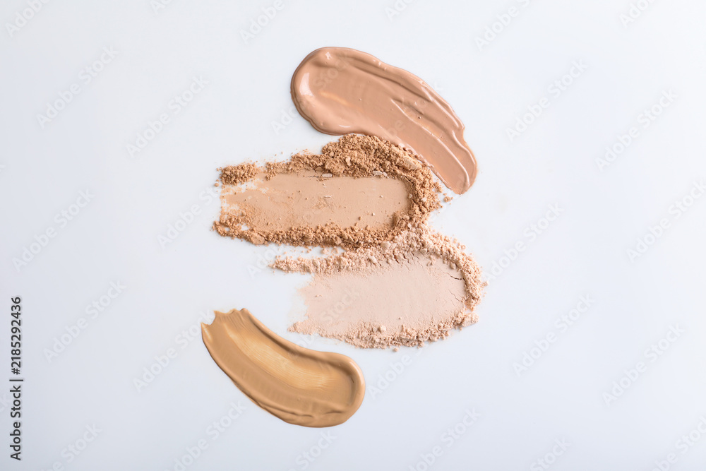 Obraz premium Swatches of different foundations and face powders on white background, flat lay
